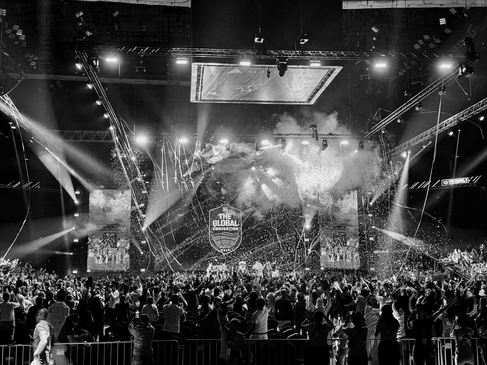 Convention stage with dramatic lighting, confetti, and a full audience
